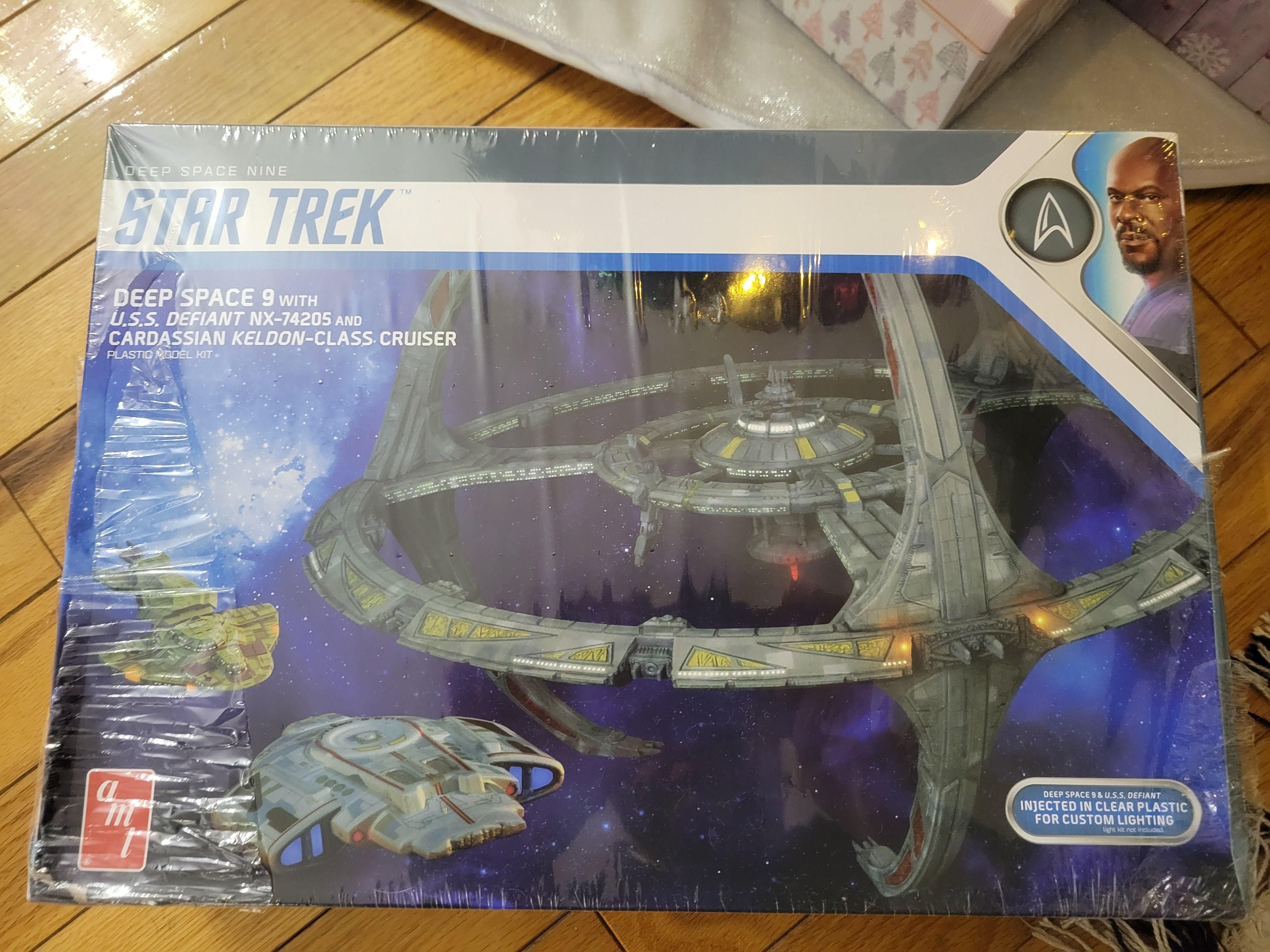 The box for a model set for Star Trek's Deep Space Nine. It includes the U.S.S. Defiant and a Cardassian Keldon-Class Cruiser. The box features both the station and smalelr ships floating on a purple-black starry background. The bottom right caption indicates it's injected in clear plastic for custom lighting. A profile of Captain Sisko is in the top right corner of the box.