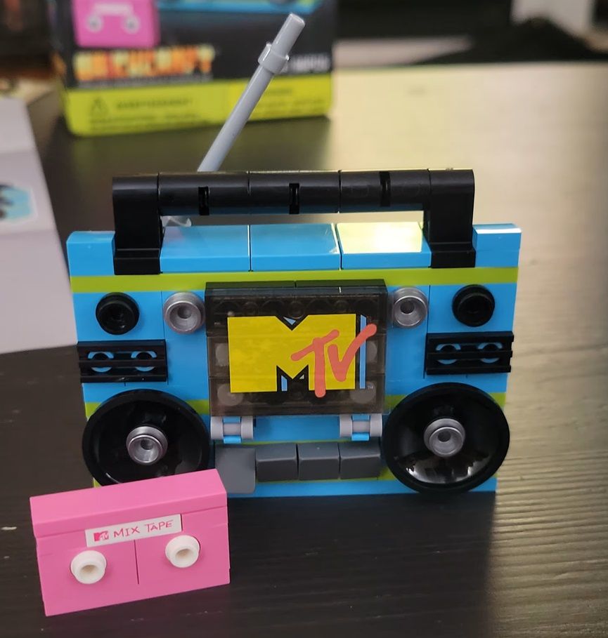 A completed brick building toy. The MTV boombox is sitting behind a pink mixtape.