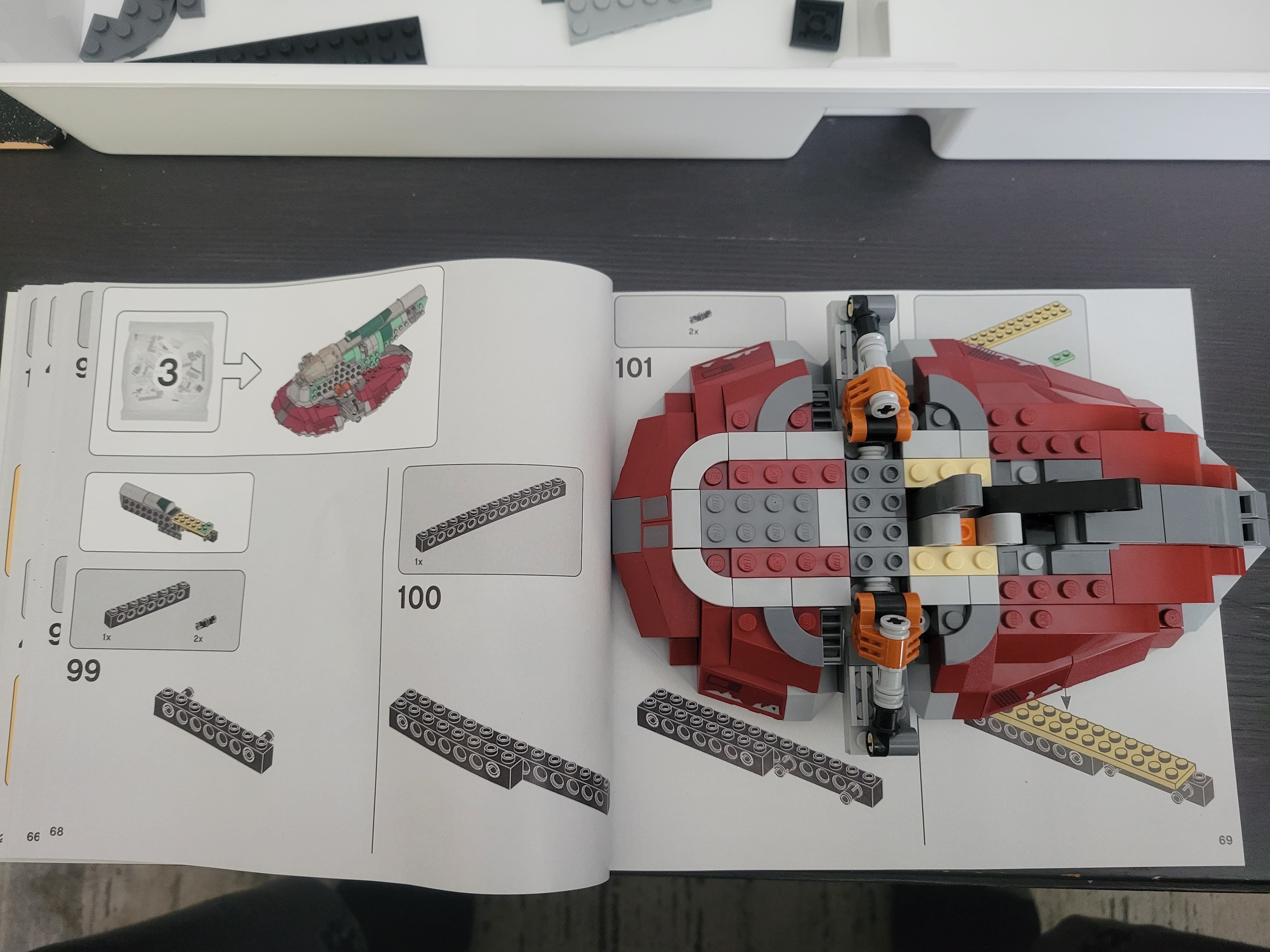 A partly complete Boba Fett's Starship sitting on the right side of a LEGO instruction booklet. A white plastic tray can be seen at the top with some LEGO parts.