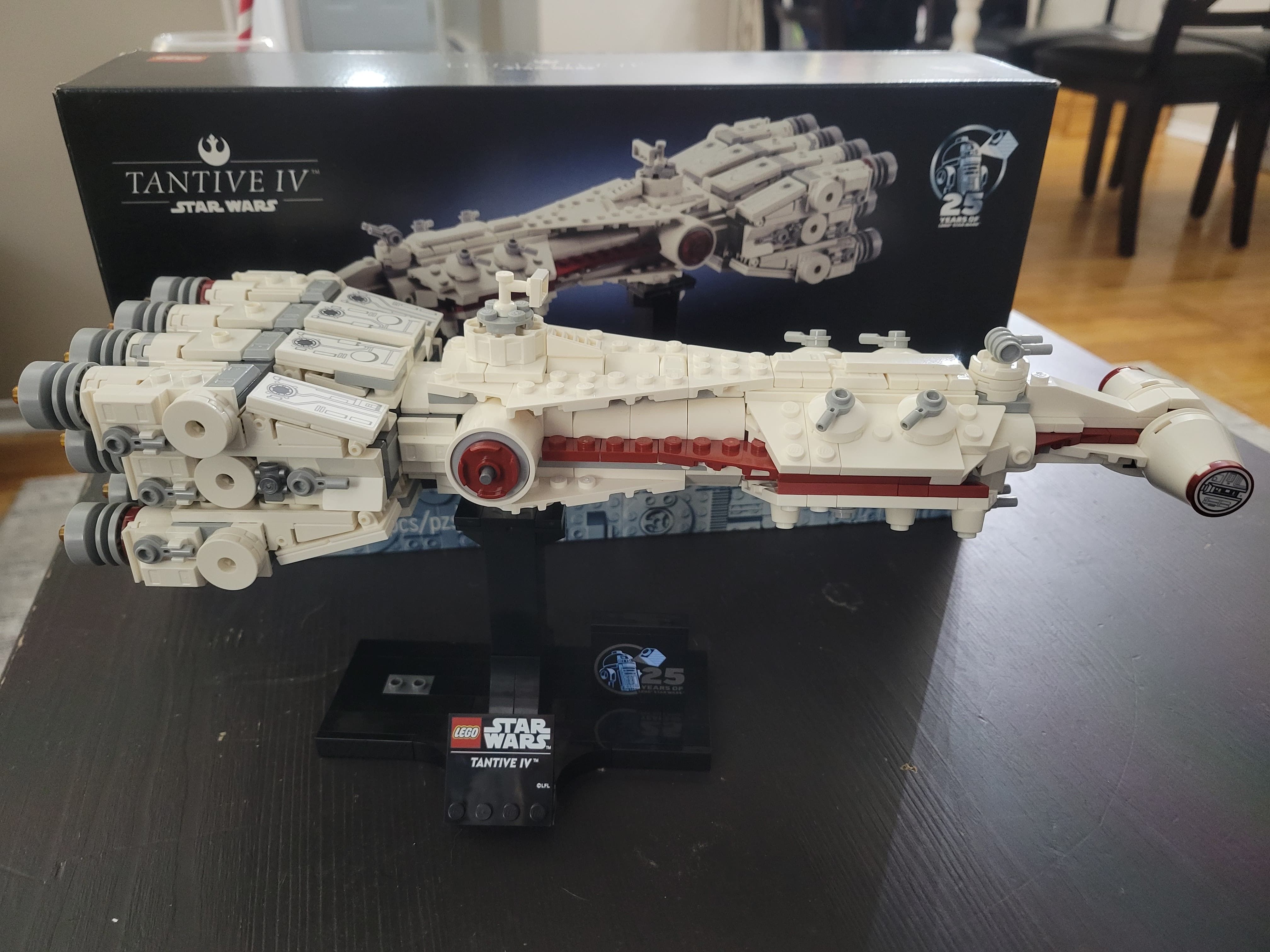 The completed Tantive IV set. The front of the ship is on the right side and sits on a black display stand in front of the original box.