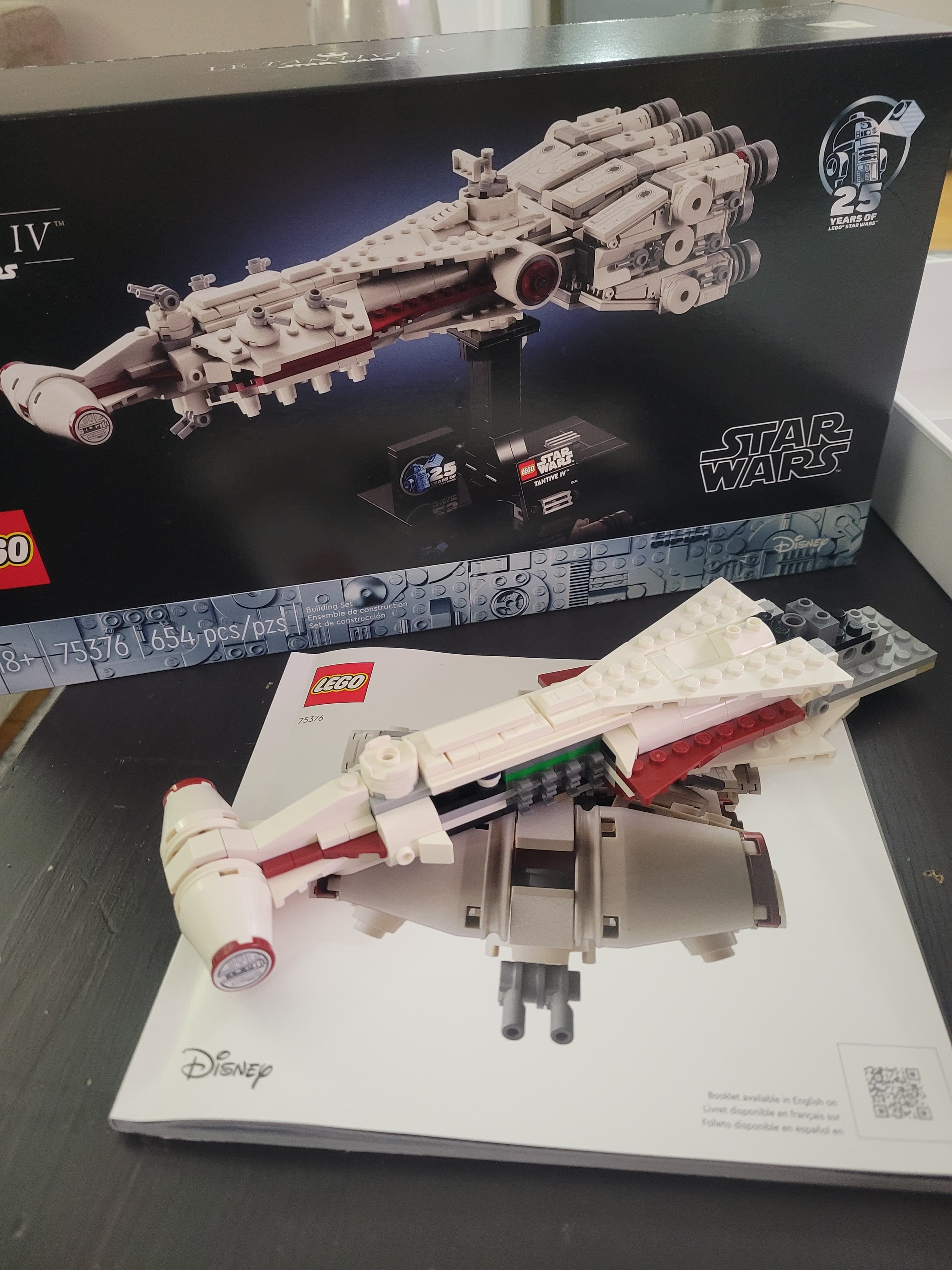 The partially completed set after the first session. The front of the ship is facing to the bottom left of the picture and is missing the big engines that is the signature feature of the Tantive IV. The model sits on top of the instruction manual and in front of the original box.